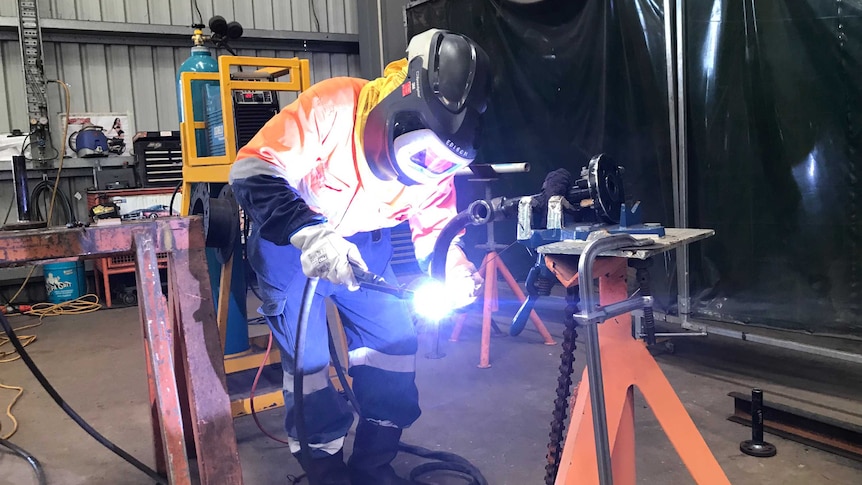 A man welds metal at steel fabrication factory in Darwin.