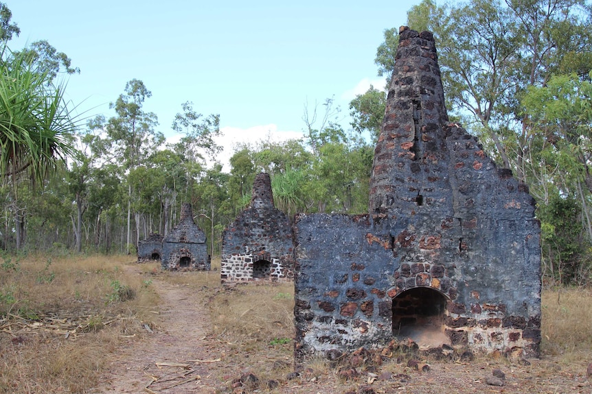 A row of remains of a settlement, surrounded by Australian bush, in the Northern Territory.