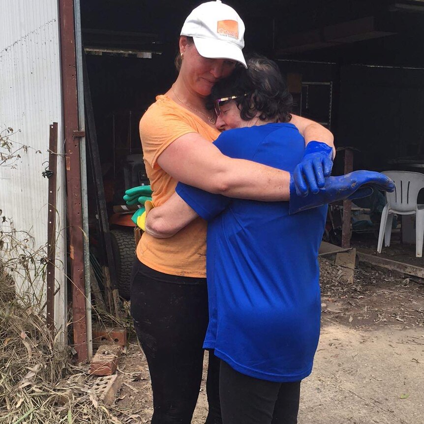 A woman offers comfort to a distressed flood victim in Logan