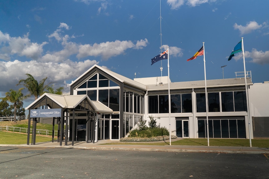A two-storey council building, with the Australian, Aboriginal, and Torres Strait Islander flags flying in front of it.
