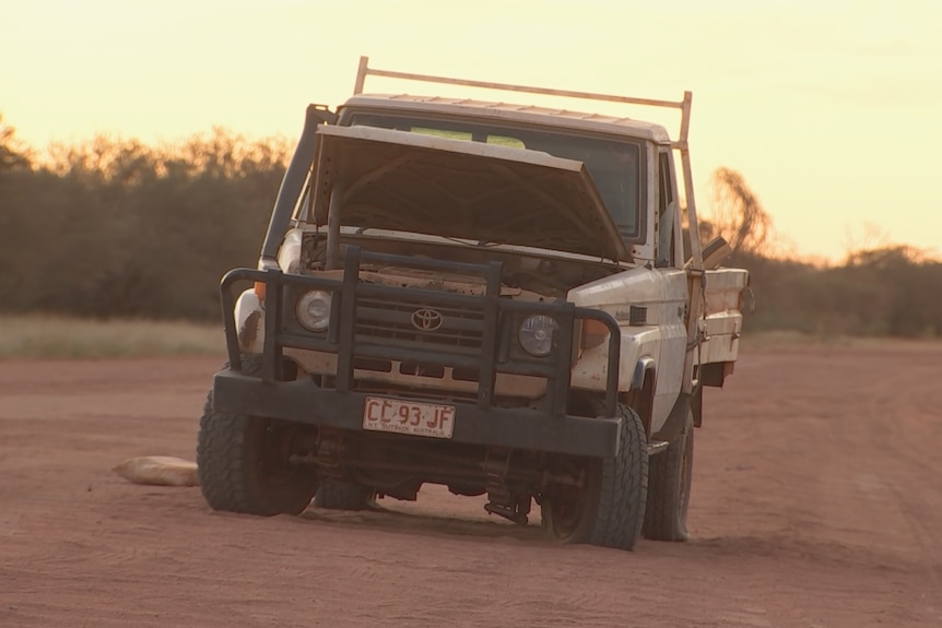 A broken-down four wheel drive on the side of a dirt road.