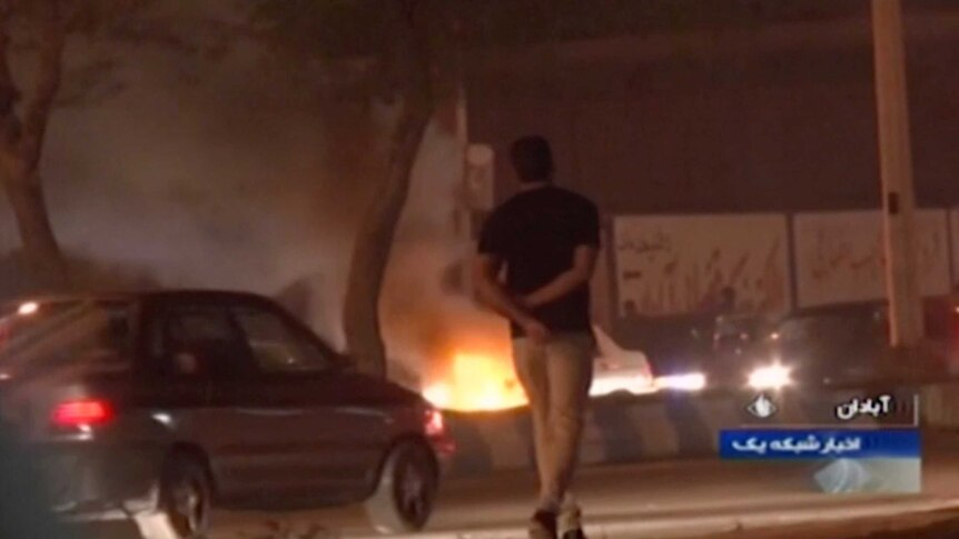 A man walks past a fire set by protesters in Abadan, Iran.