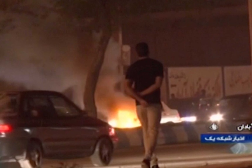 A man walks past a fire set by protesters in Abadan, Iran.