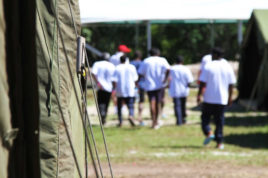 Out of focus men stand near tents.