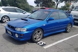 A blue sedan in a car park