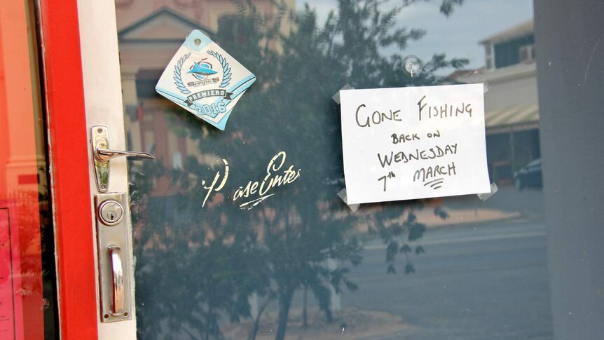 A piece of A4 paper on a door, with text on it which reads: Gone fishing back on Wednesday 7 March.