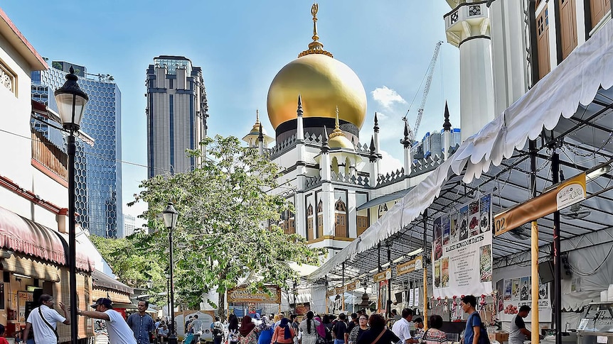 Looking down a well-appointed alleyway, you see a large mosque with a gold-top in the distance, lined with food stalls.