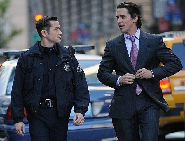 Joseph Gordon-Levitt in a police uniform and Christian Bale in a suit in The Dark Knight Rises. 