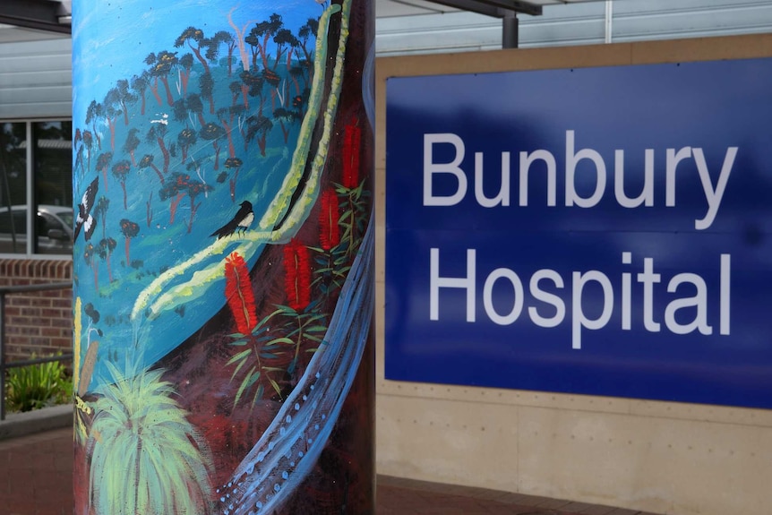 A sign saying Bunbury hospital, next to a pillar with a mural showing flowers, trees, bush.