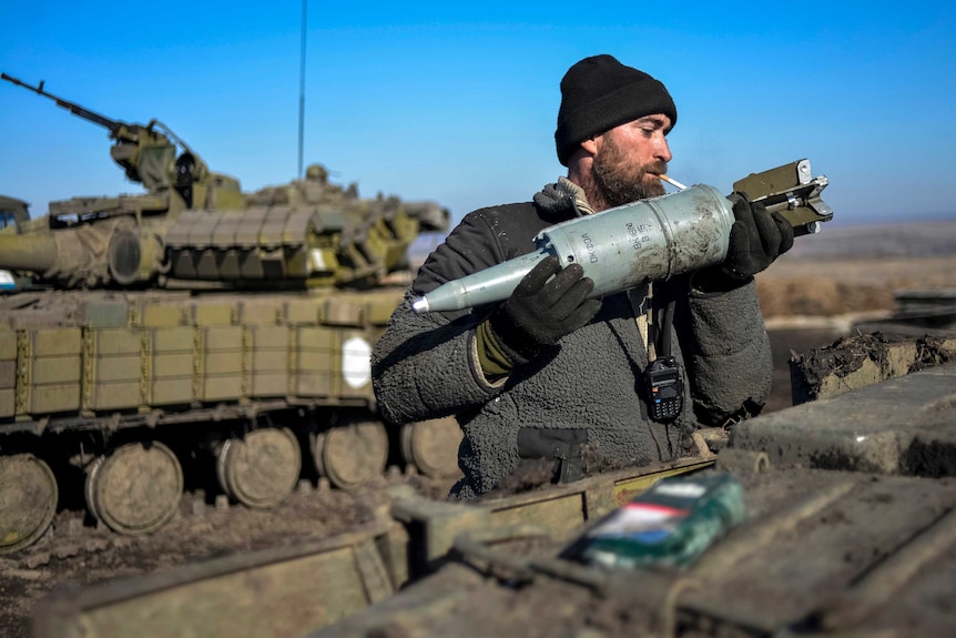 Ukrainian soldier loads ammunition into his tank