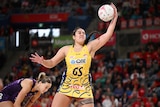 Palavi takes the ball one handed in a yellow and blue dress as the crowd watches on