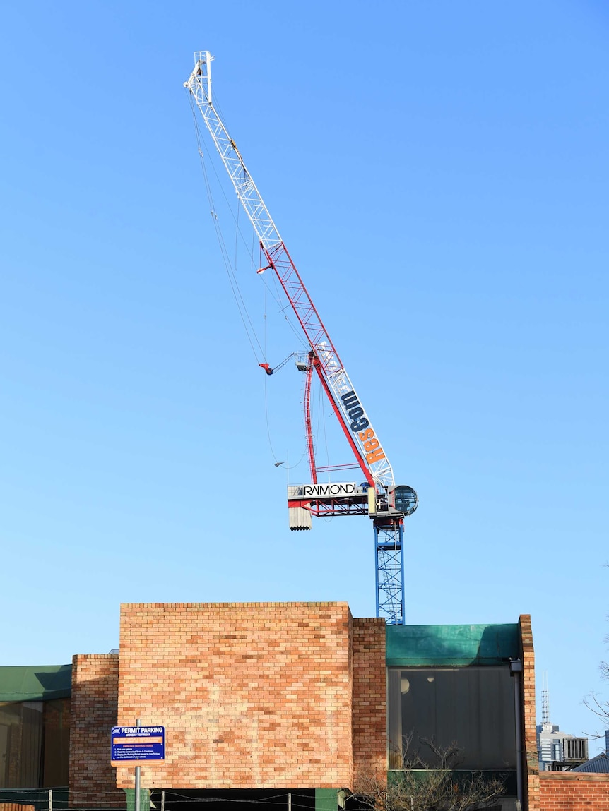 A crane can be seen above and behind a building.