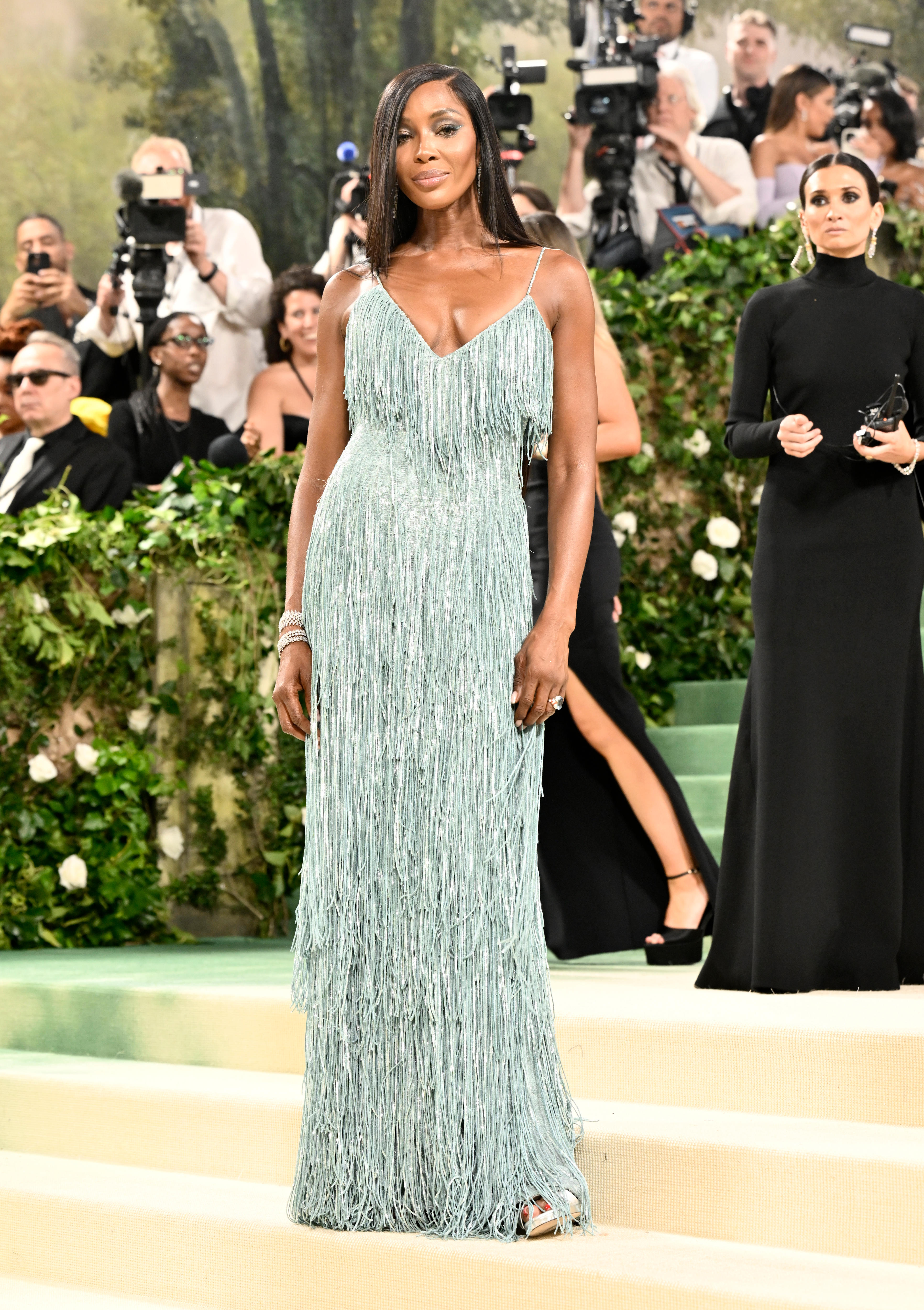 Naomi Campbell wearing a strappy long blue gown with shaggy fronds