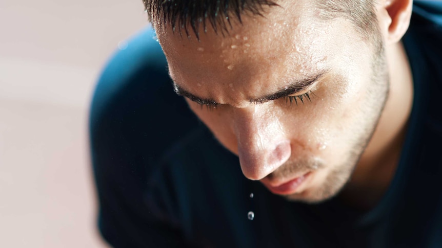 Close up of a male athlete dripping sweat and looking exhausted