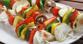 Barbequed vegetable skewers on a plate.