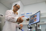 Researcher Qi Fang holds a portable imaging device in a laboratory.