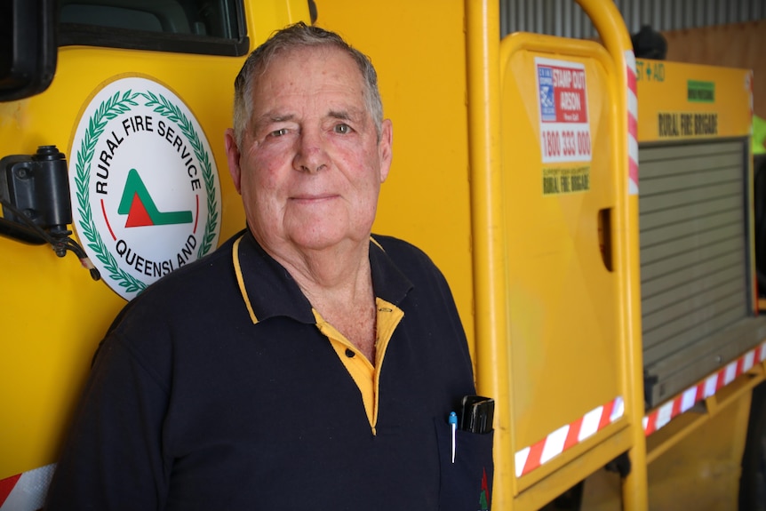 a head-and-shoulders portrait of a man standing in front of a fire truck