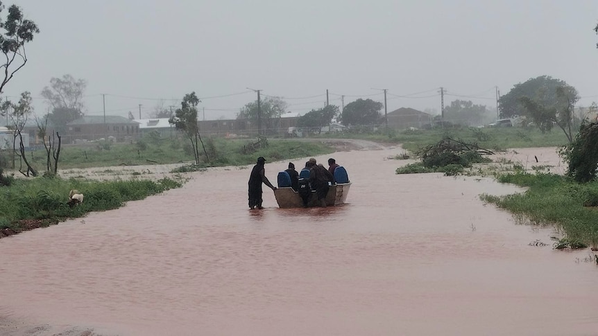 People are seen in a boat in floodwaters in the remote community of Pigeon Hole.