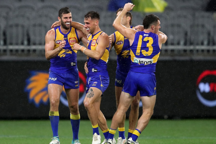 Four West Coast Eagles AFL players embrace as they celebrate a goal against Hawthorn.