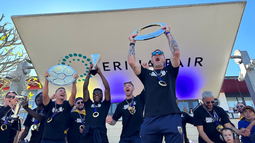 Central Coast Mariners players on stage at a celebration for their historic a-league win