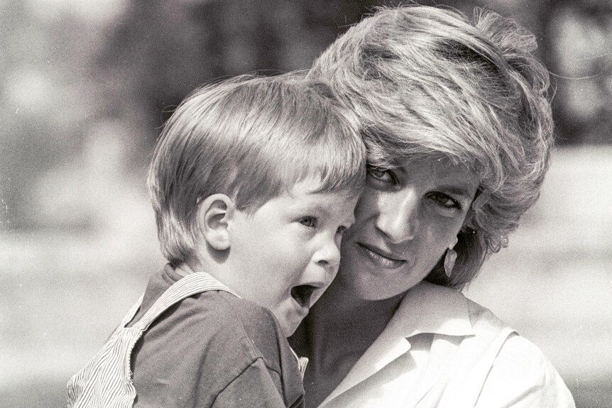 A black and white image of Diana holding a very young Prince Harry in her arms