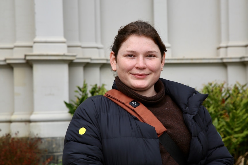 A woman looking directly ahead wearing a black jacket.