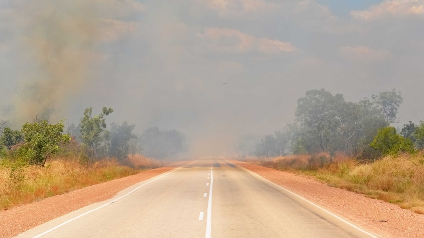 Smoke hangs over a road in the bush