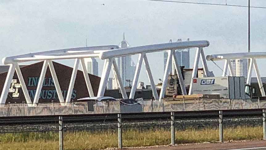 A truck carrying a large white bridge section on the freeway.