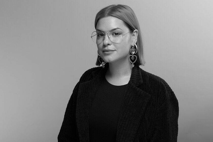 Liana in a black and white photo, wearing glasses. 