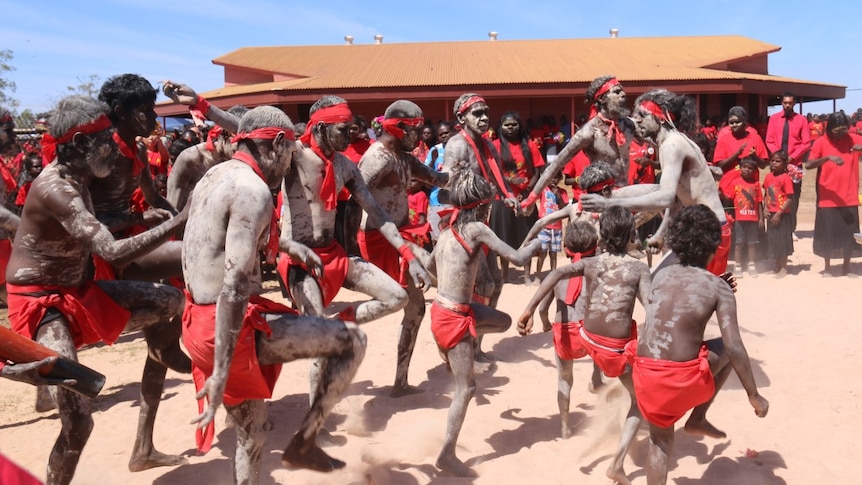 Dancers perform in body paint and red bandannas