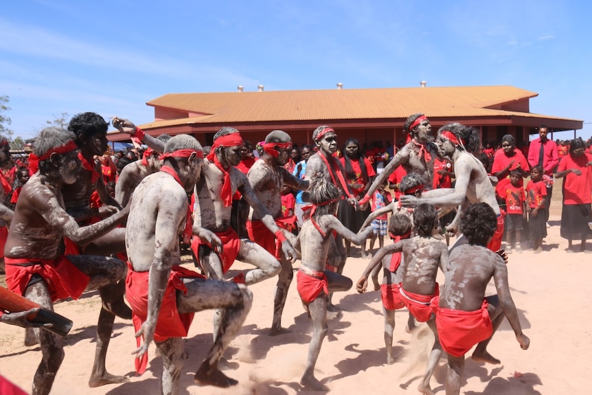 Dancers perform in body paint and red bandannas