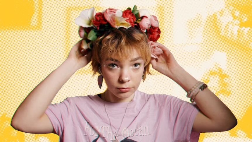 Woman in pink t-shirt adjusts a floral wreath on her head 