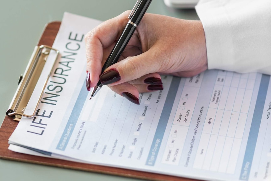 A woman's hand signing a life insurance document