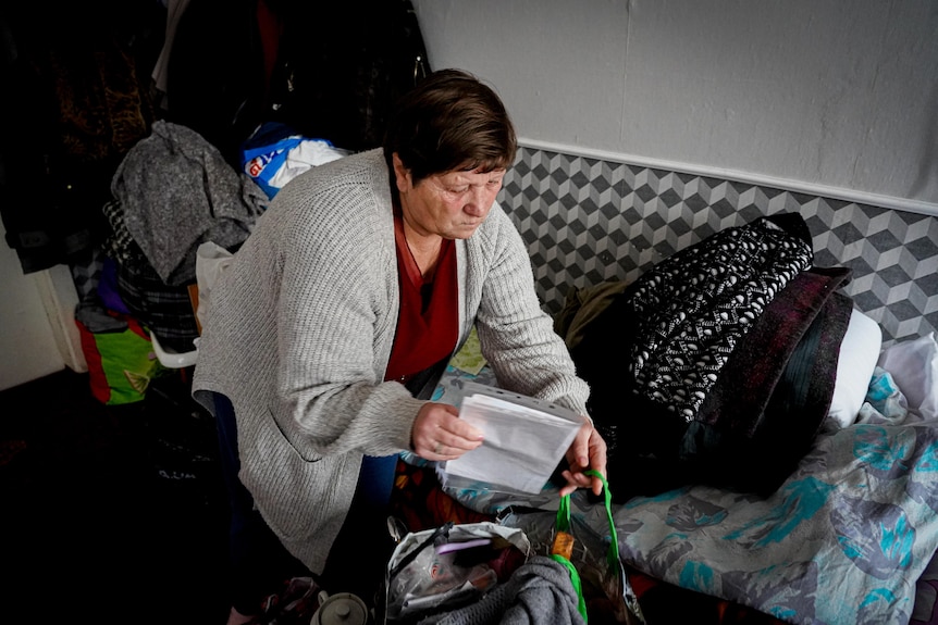 An older woman with cropped hair packing up a bag 