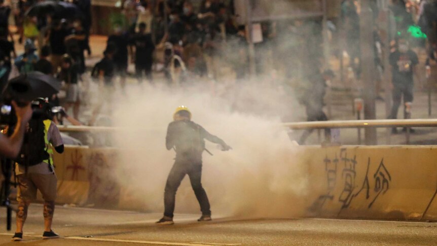 A protester tries to extinguish an exploded tear gas shell in Hong Kong