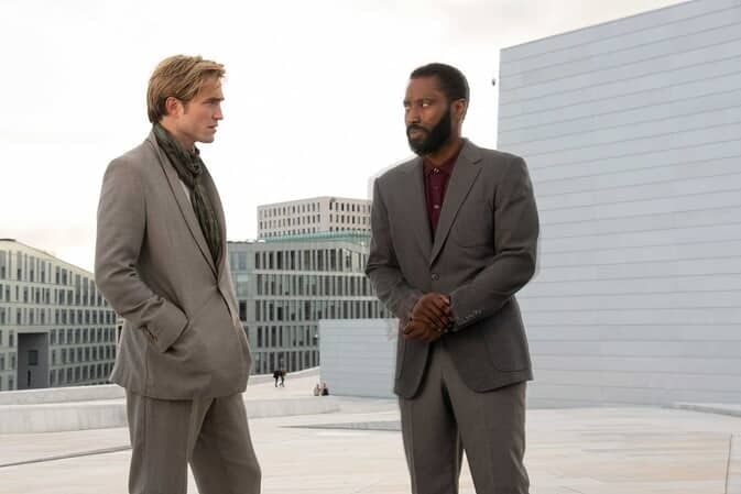 Robert Pattinson and John David Washington stand together in suits in a picture from the movie Tenet.