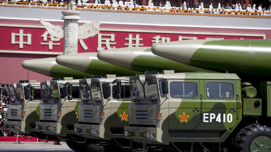 Wide shot of a line of military vehicles with missiles on their roofs.