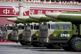 Wide shot of a line of military vehicles with missiles on their roofs.