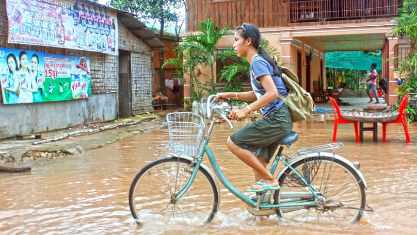 Girl cycles through Cambodian floodwaters