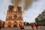 Smoke and the glow of a fire can be seen billowing from the Notre Dame cathedral from behind the two iconic towers.