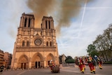 Smoke and the glow of a fire can be seen billowing from the Notre Dame cathedral from behind the two iconic towers.