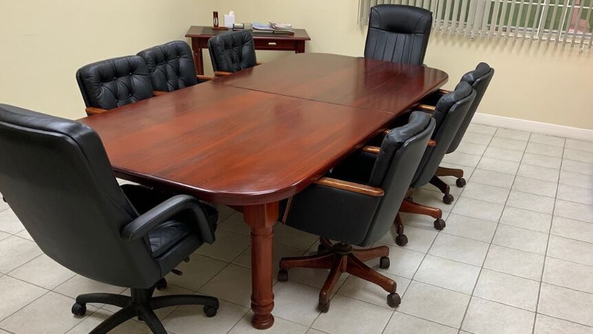 A wooden desk with leather chairs.