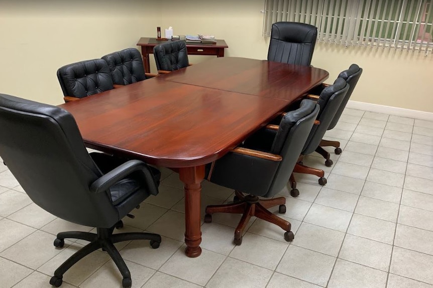 A wooden desk with leather chairs.