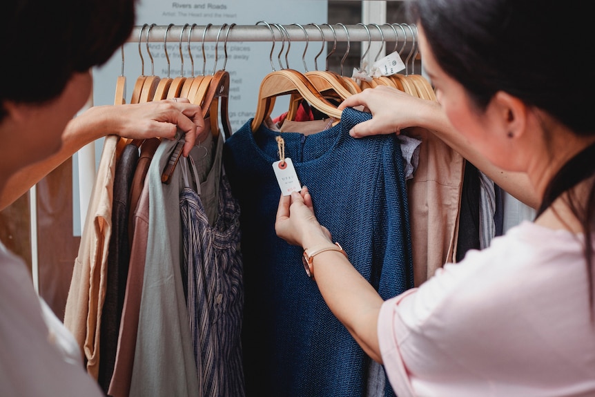 Two women browsing through clothes hung on a clothes rack