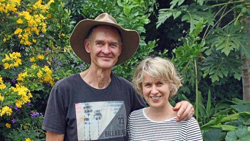 A man and a woman stand in front of fruit treets