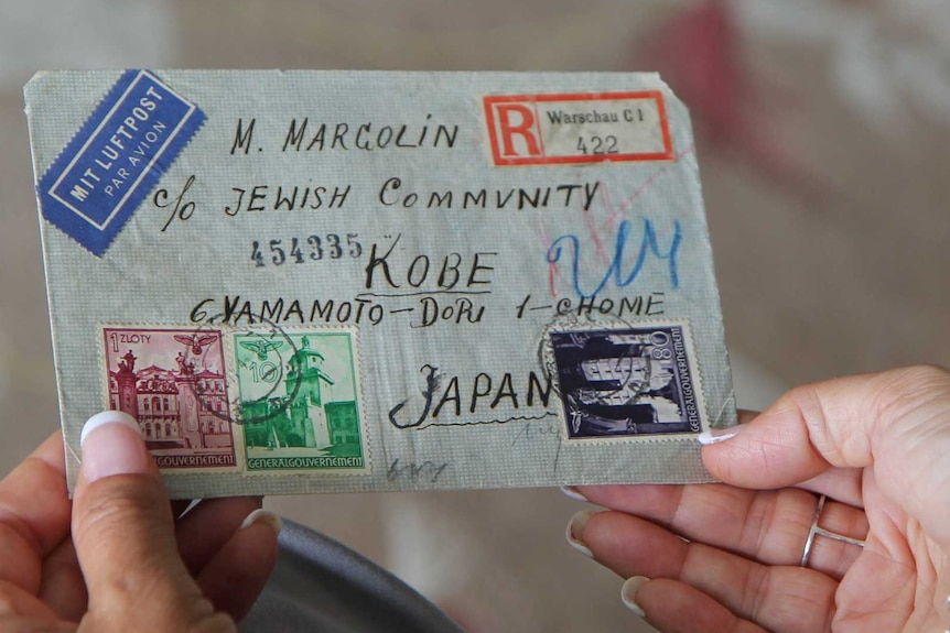 A woman holds an envelope from the Warsaw ghetto addressed to the Jewish community in Kobe, Japan.