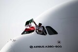 The Iranian pilot of an Airbus A380-800 aircraft holds an Iranian national flag.