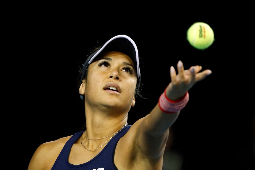 A close up of a tennis player throwing ball in air before serve.