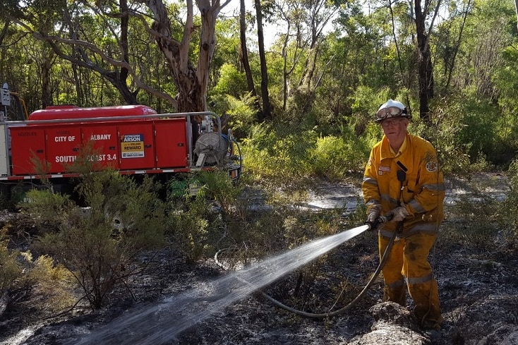 Firefighter stands in front of fire truck with hose