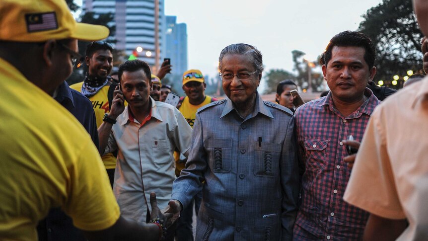 Former prime minister Mahathir Mohamad (C) shakes hands with supporters